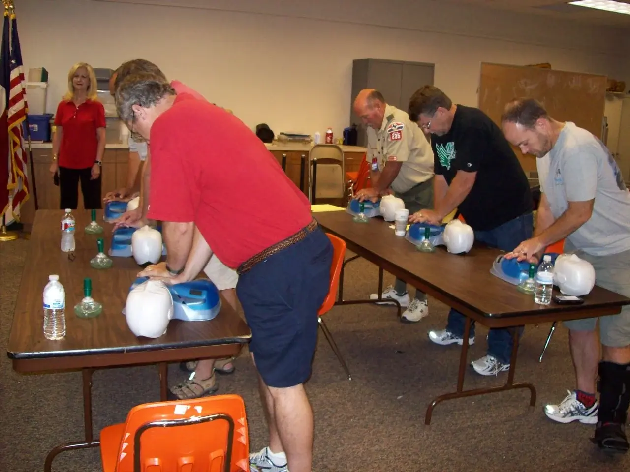 A class practising two-handed chest compressions on manikins set along the training tables.