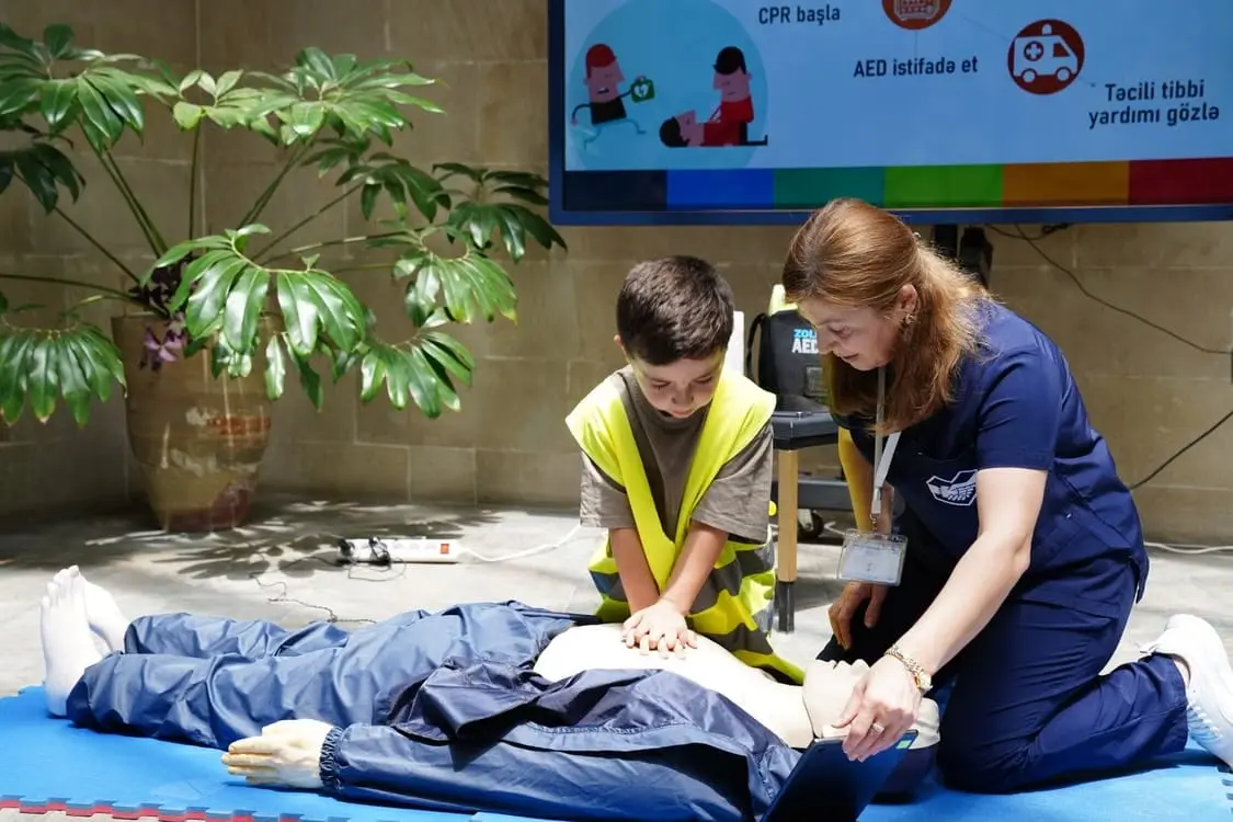 An instructor guiding a student through chest compressions on a manikin.