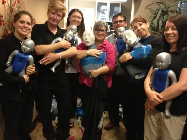A class group holding their adult training manikins at the end of a session.