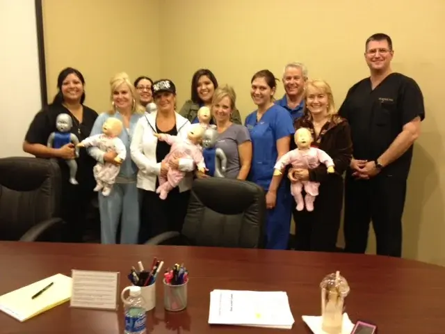 A class group holding their infant training manikins at the end of a session.