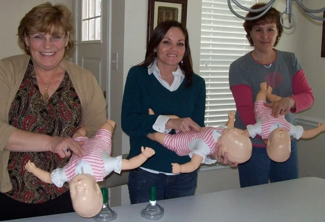 Three students each holding an infant training manikin during an infant CPR class.